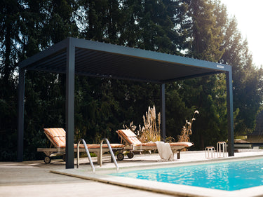 A PERGOLUX Sundream S2 pergola with an electric roof, situated by a poolside, providing shade to outdoor seating area.