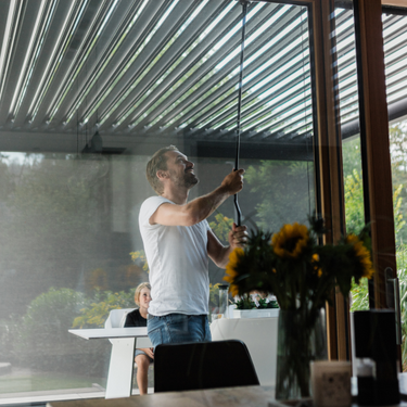 Man adjusting manual pergola in a modern home setting