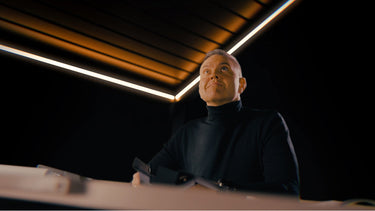 Person in a dark outfit sitting at a table with a modern interior background