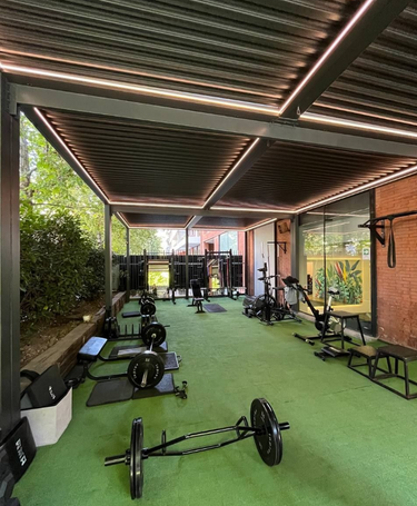 Gym interior with green flooring and various exercise equipment. Gym under. a pergola
