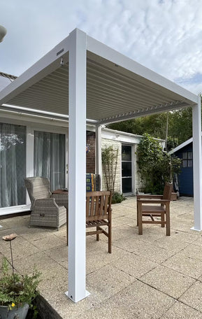 White pergola structure in a backyard setting with patio furniture.