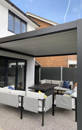 Outdoor patio area with pergola, furniture, and table under a clear blue sky.