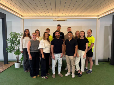 Group of australian people posing for a photo in an indoor setting under a pergola with a plant and modern decor.