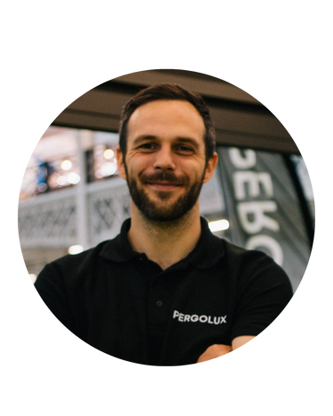 Man wearing a black shirt with 'Pergolux' logo in an indoor setting