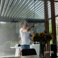 Man adjusting manual pergola in a modern home setting