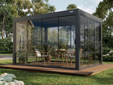 PERGOLUX glass wall pergola with dark grey metal framing and clear tempered glass panels enclosing a wooden deck dining area