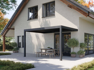 Matte black attached pergola with closed louvres over wooden dining set