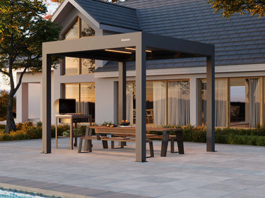 Two-tone dark grey PERGOLUX motorised pergola frame with interior lighting over paved backyard entertaining zone