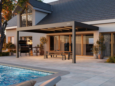 Extended dark grey louvered roof Pergola 4 Pro Max providing shade over barbecue grill on terrace