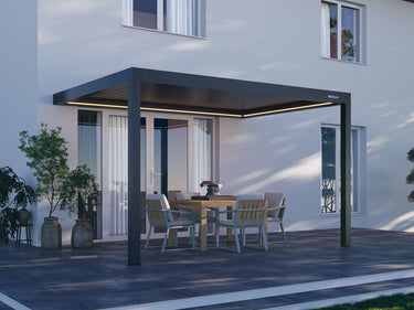 Dark grey matte Pergola 4 Pro with warm LED beam lighting over wooden dining set on paved patio