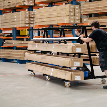 Person maneuvering a cart with stacked boxes in a warehouse setting