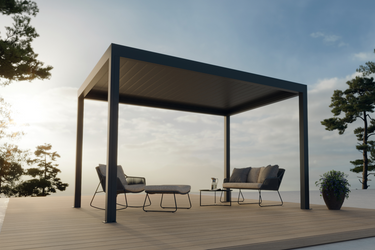 Outdoor patio with pergola, chairs, and table on a wooden deck with trees and sky in the background.