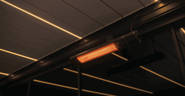 Close up orange infrared heating element beneath dark pergola louvres
