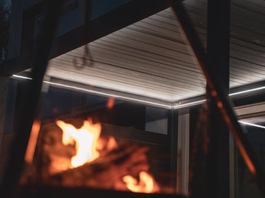 Pergolux Pergola med Pergolux LED lys, varm hvit. Bålpanne flamme i forgrunnen.