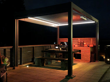 PERGOLUX LED lights installed in pergola gutter illuminating outdoor dining patio at night